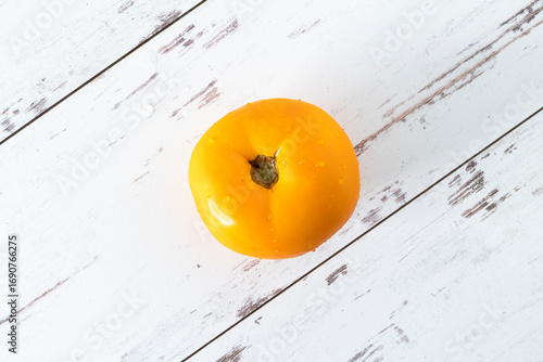 Yellow tomato, fresh from farmers market, on white-washed distressed wood surface