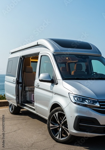 Silver camper van with open door overlooking coastal scenery