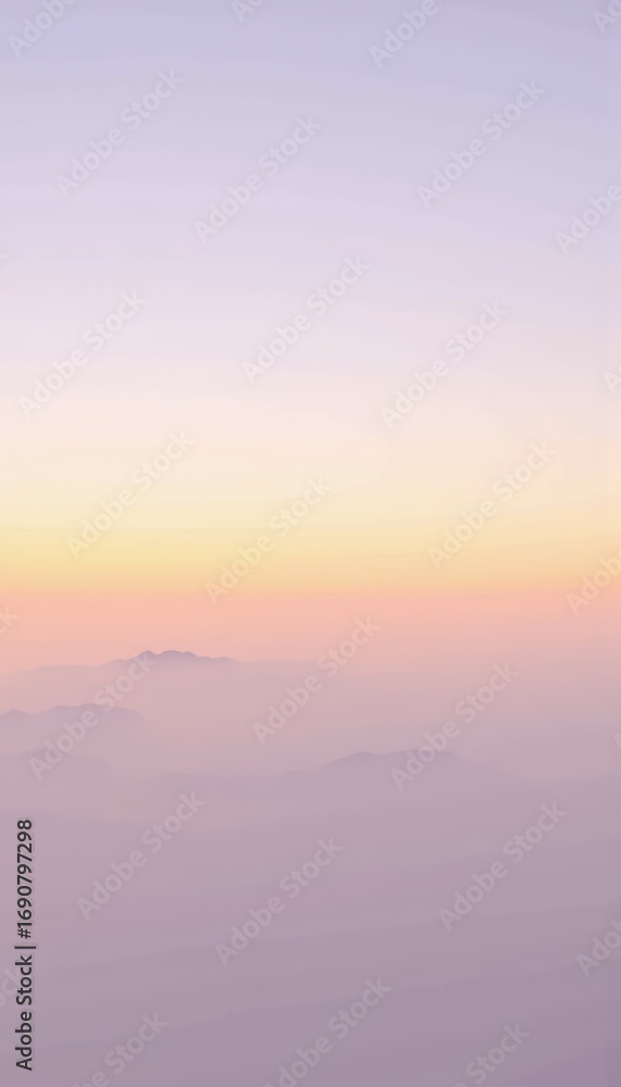 Fototapeta premium Serene Mountain Landscape at Sunrise with Softly Blended Hues of Pastel Pink and Orange Above Shrouded Peaks, Creating a Dreamlike Atmosphere