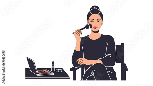 Young woman applying makeup with a brush while sitting in a chair with a laptop and cosmetics on a table