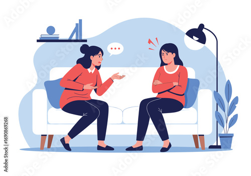 Two women talking while sitting on a couch in a living room with a lamp and plant