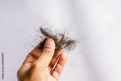 Roll of hair loss in hand on white background