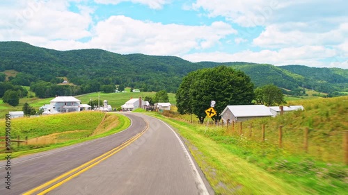 Blue Grass village in Highland county, Virginia countryside, car driving point of view by farm shed barns houses at Appalachian mountains