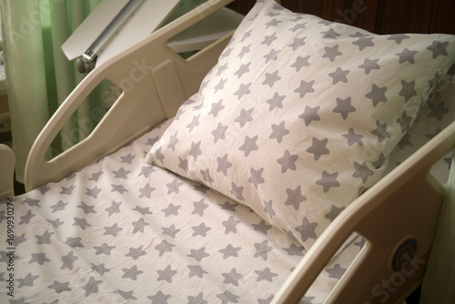 Empty patient bed with clean sheet and pillow in hospital room. Healthcare facility for recovery and medical care.