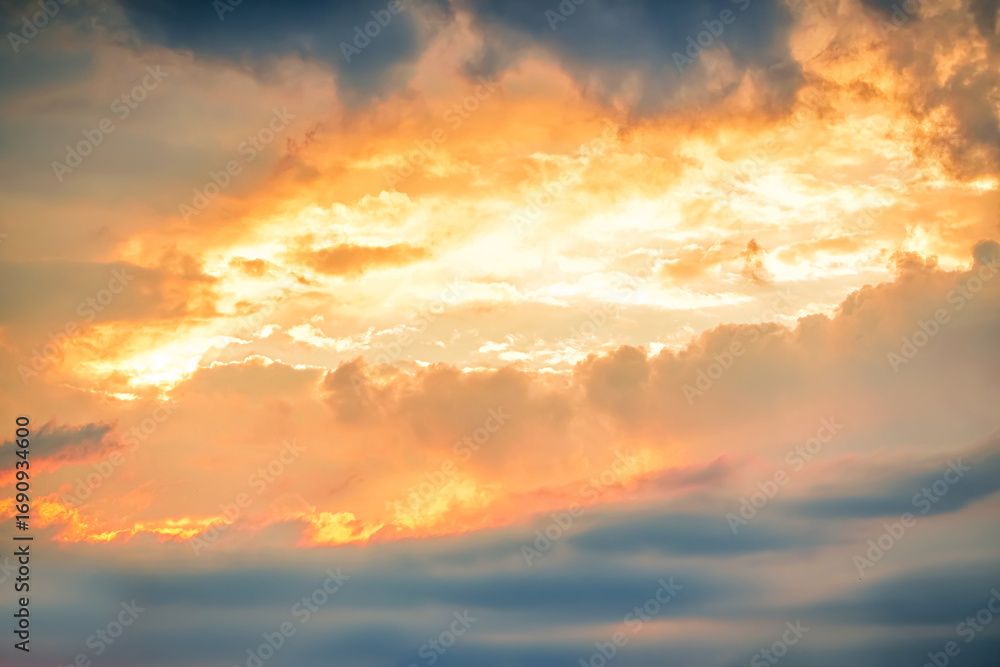 Fototapeta premium Dramatic sunset clouds creating a vivid canvas of vibrant colors in the evening sky over a tranquil landscape