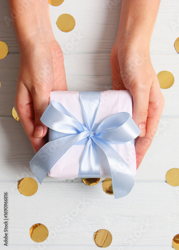 Wallpaper Mural gift in female hands on a colored background with confetti top view.. Vertical photo format Torontodigital.ca