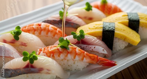 A platter of assorted sushi nigiri with shrimp, fish, and egg, garnished with green sprouts, presented on a white rectangular plate animated 4k video