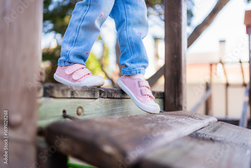 Принти на полотні Toddler carefully placing her feet on playground equipment, enjoying outdoor pla