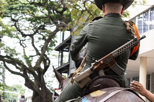 Carabinero on horseback carrying rifle, Mounted police officer with firearm, Colombian carabinero in action. High quality photo