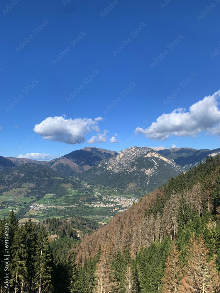 Fototapeta premium Mountain town surrounded by green valley and rocky peaks