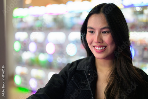 Happy young woman playing arcade video games indoors