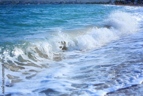 Ocean waves crashing on sandy beach. Sea waves breaking on shore. Nature splash on summer day. Sea wave crashing on beach. Splashing sea water with foam.