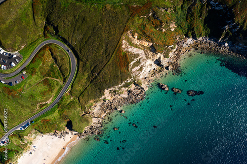 Aerial top down view of winding road with a car and a parking lot at Keem Beach on Achill Island in Ireland