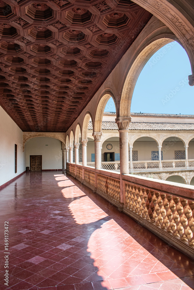 Fototapeta premium Gallery with semicircular arches, columns, and wooden ceiling panels in the Santa Cruz Museum in Toledo, Spain.
