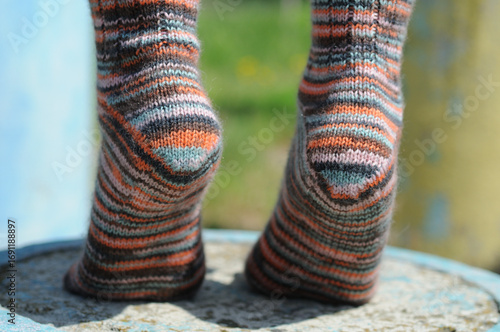 Close-up of young woman's legs in colorful socks. Knitting socks by hand.