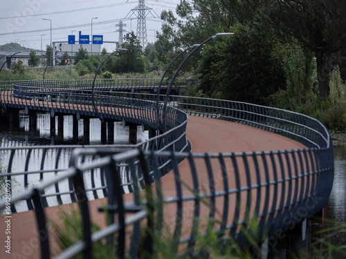 Modern bridge with distinctive curved architecture spanning water with urban infrastructure visible