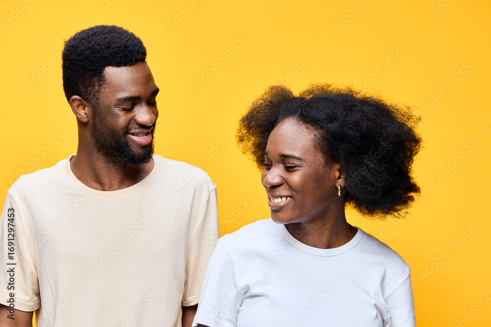 Fototapeta premium Happy young couple with natural hair, smiling against a bright yellow background, showcasing love, joy, and confidence in a vibrant setting