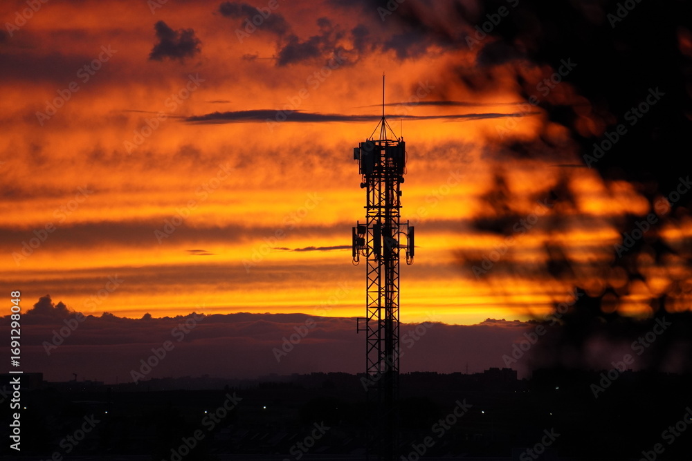 Naklejka premium Telecommunication tower at sunset with dramatic sky