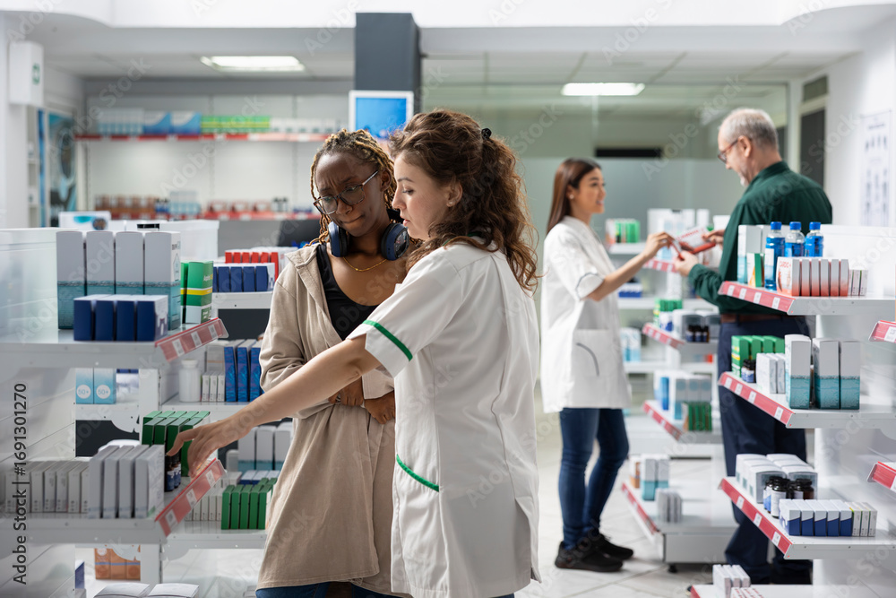 Obraz premium Black female customer examining medicaments and pills with a pharmacist, learning about proper dosage, treatment and healthcare remedy with guidance in a retail pharmacy shop.