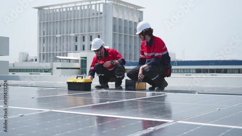 Engineers inspecting rooftop solar panels with laptop

