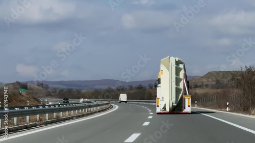 Truck transporting oversized load swimming pool on highway in rural landscape on clear day