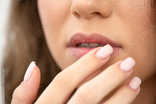 Young woman touching her dry lips, close up. Skin care and lip care concept. Selective focus.