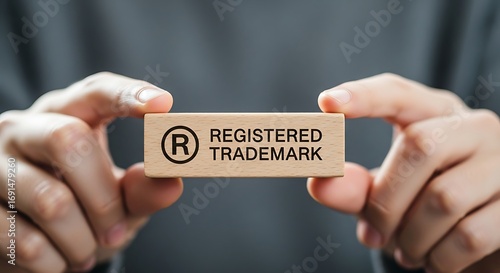Hands holding a wooden block with registered trademark symbol and text Keywords: registered trademark