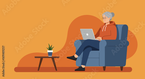 Content senior woman uses a laptop comfortably in her armchair at home, symbolizing modern connectivity, independent living, and digital engagement for the elderly.