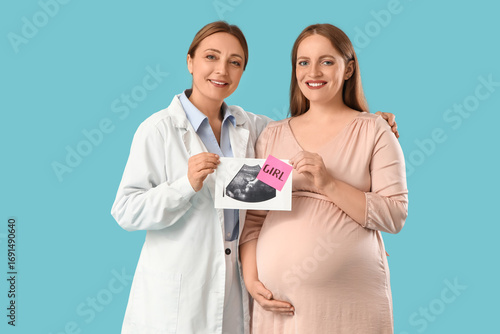 Young pregnant woman and doctor with sonogram image of girl on blue background
