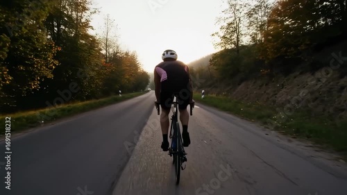 Cyclist riding on a picturesque road at sunrise, embracing freedom and fitness
