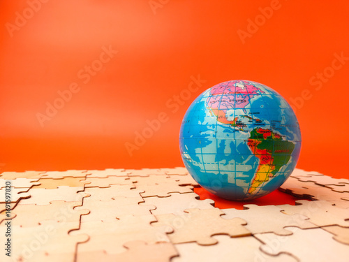 The image shows a colorful globe, which is a puzzle, resting on a surface covered with scattered, unassembled puzzle pieces