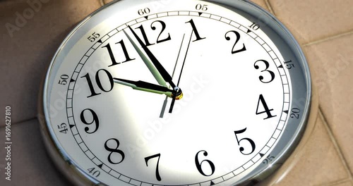Time-lapse of a classic wall clock with moving shadows and sun rays reflecting across the surface, creating dynamic patterns of light and time flow.

