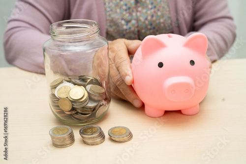 Retired elderly woman counting coins money with piggy bank and worry about monthly expenses and treatment fee payment.
