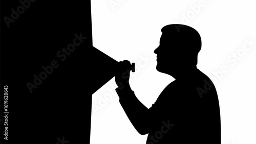 Silhouette of a man looking through a device attached to a dark structure against a white background