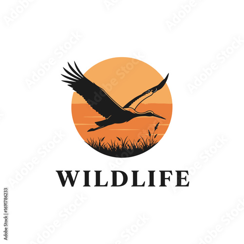 A graphic logo of a silhouetted stork or crane flying over a marshy wetland against a large orange sun.