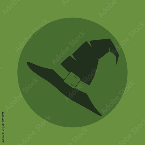 A dark silhouette of a classic witch's hat with a buckle, tilted inside a dark green circle on a lighter green background.