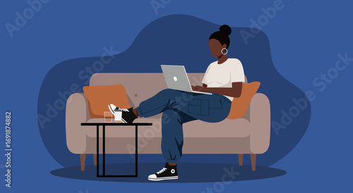 Young woman works remotely from home on a laptop, comfortably seated on a sofa. Represents freelance work, flexible lifestyle, and modern productivity.