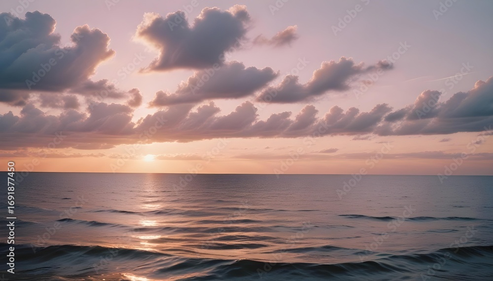 Obraz premium Sunset over the ocean with soft clouds