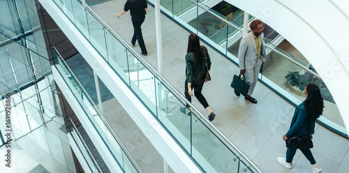 Canvastavla Businesspeople walking through modern office building interior