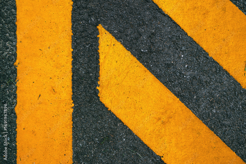 Fototapeta premium Yellow painted road marking on asphalt surface, urban traffic symbol background.