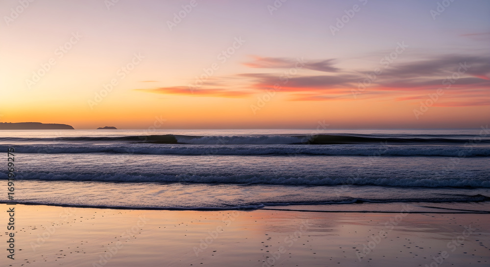 Obraz premium Serene sunset over the ocean with gentle waves lapping on a sandy beach, casting a warm glow across the sky and water