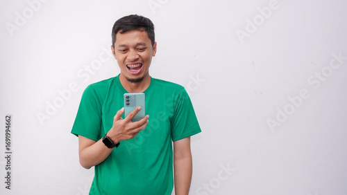 Asian man smiling friendly when holding his mobile phone