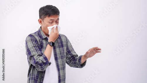 Asian man cover his nose and mouth with tissue when sneezing isolate on white background. wearing green flannel