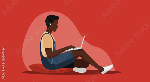 Focused young Black man working remotely on a laptop with earbuds while sitting comfortably. Ideal for online education or digital business.