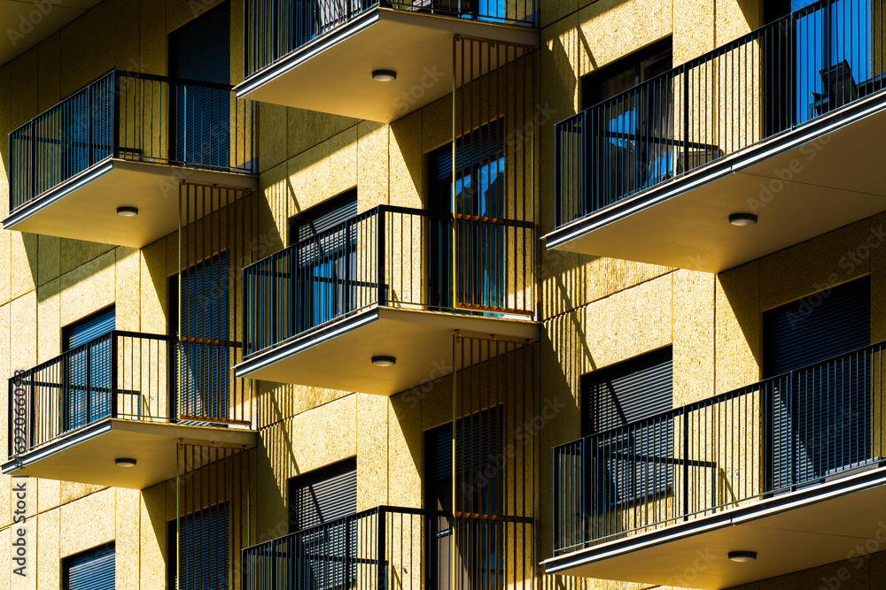 Fototapeta premium Residential building façade with yellow balconies and railing symmetry captured from dramatic low-angle perspective.