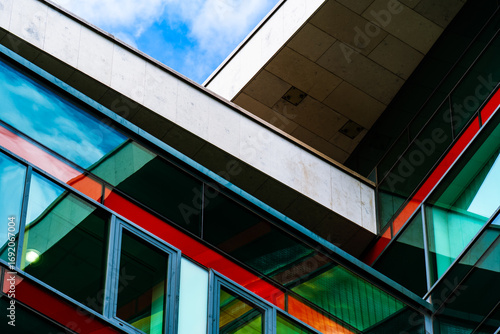 Modern building with colorful glass panels and sharp geometric lines creating dynamic architectural urban composition.