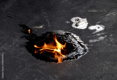 A burn test on a puddle of fuel produced from recycled waste tires, with flames rising to show its flammability as an alternative energy source.