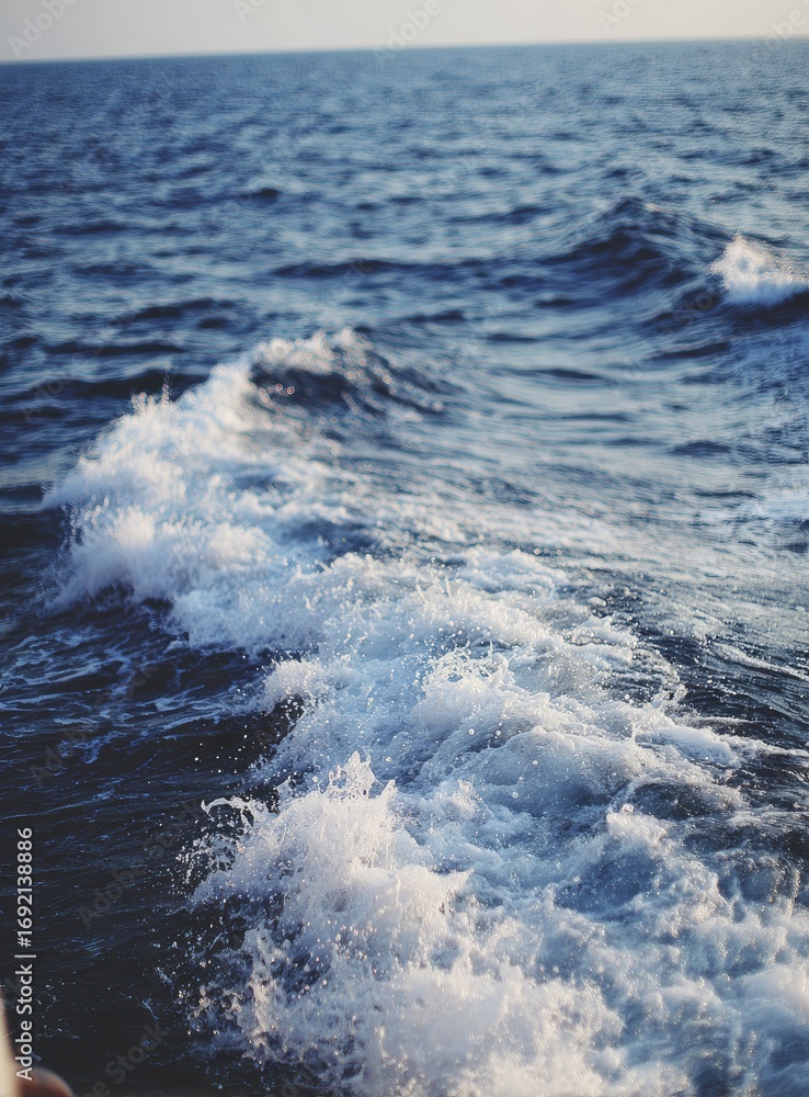 Fototapeta premium Foamy wake of a boat on deep blue ocean