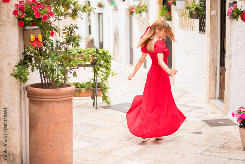 Woman twirling in red dress in Locorotondo alleyway