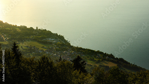 Vue plongeante depuis les sommet sur la ville et la lac d'Évian-les-Bains au lever du jour quand les premiers rayons du soleil colorent l'eau d'or et de turquoise.